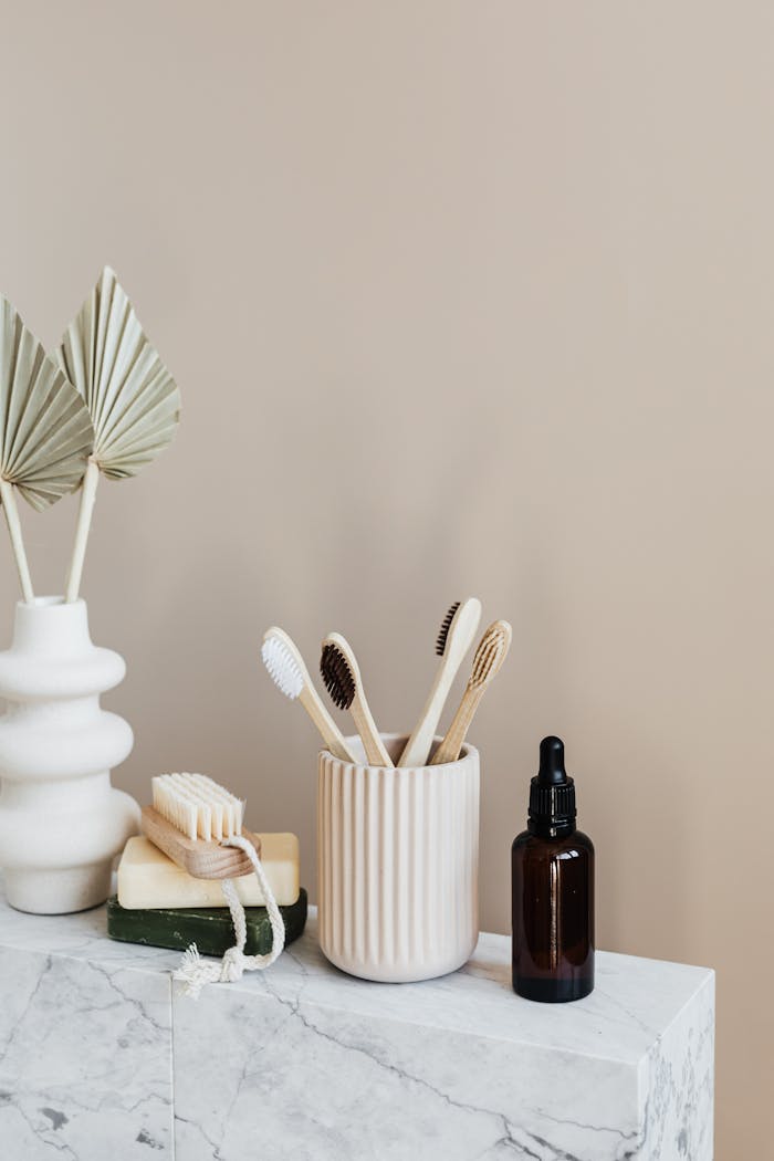 about-01 Collection of bamboo toothbrushes and organic natural soaps with wooden body brush arranged with recyclable glass bottle with natural oil and ceramic vase with artificial plant